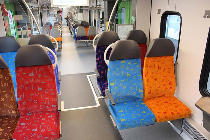 Blick in den Fahrgastraum des FLIRT 3 XL mit farbenfrohen Sitzen